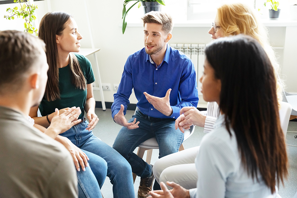 Eine Gruppe von Kolleg:innen im Gespr&auml;ch in einem Sitzkreis